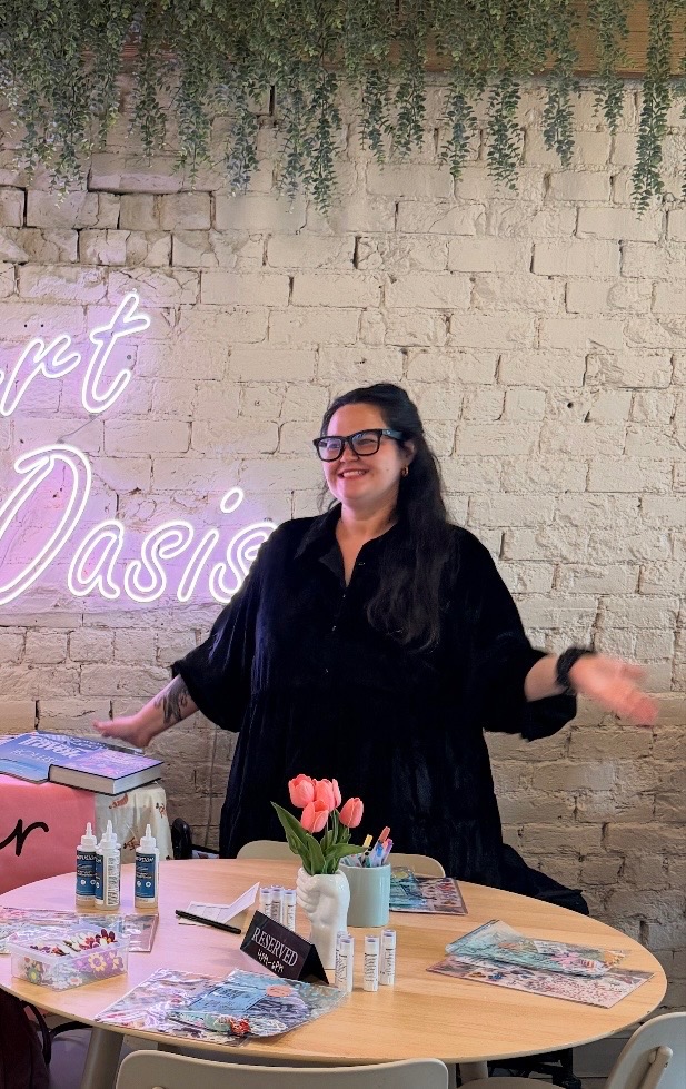 Twyla standing at a Gather and Glow craft table